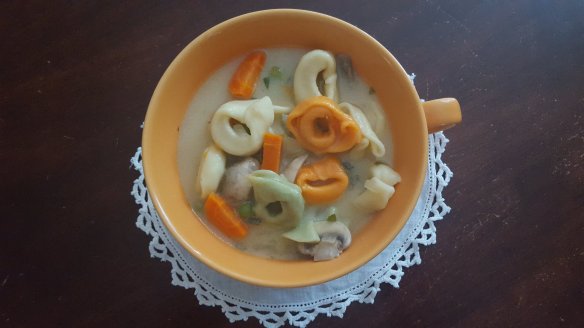 cup of soup with colored cheese tortellini and chicken broth