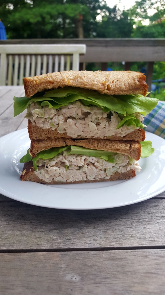 chicken salad with lettuce on whole wheat bread on a white plate
